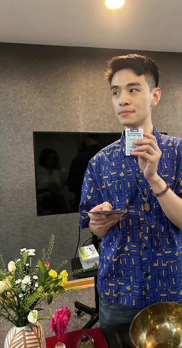 Wallance 手持一张牌卡，身旁有颂钵与鲜花