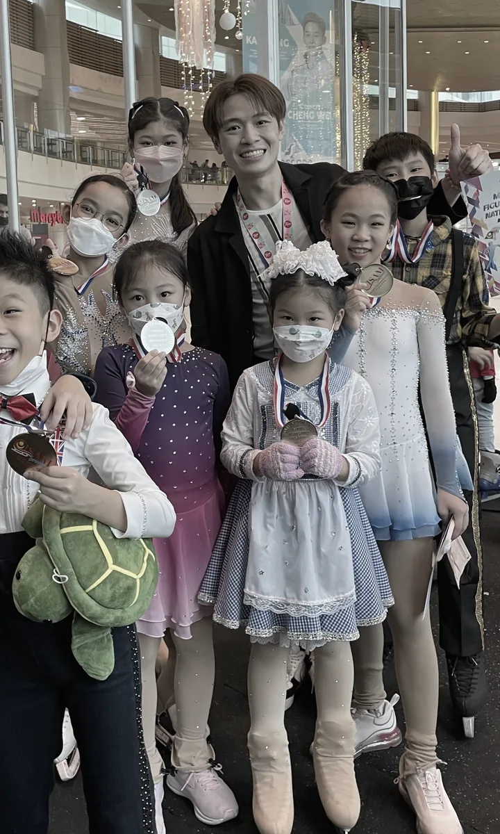 冰场边与小学员合影，孩子们拿着奖牌